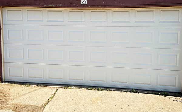 White double garage door closed on concrete driveway.