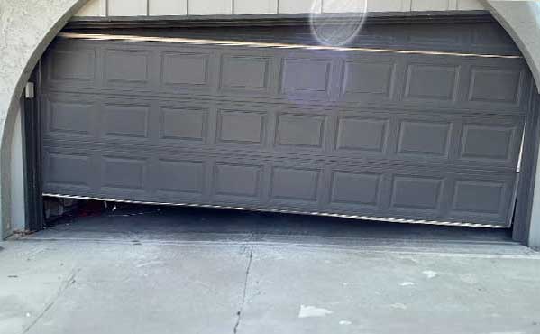 Broken garage door partly open and crooked