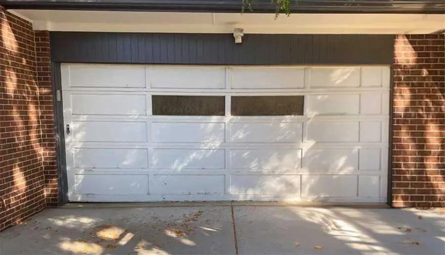 Closed white garage door on brick house