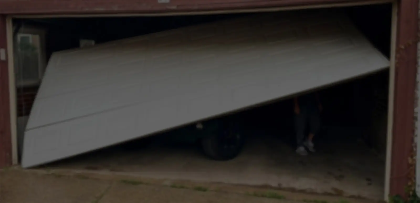 Garage door partially collapsed on parked car.