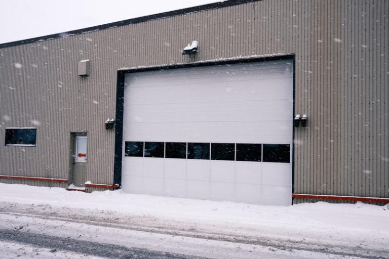 Snowy warehouse exterior with closed garage door.