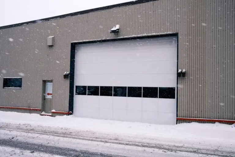 Snowy warehouse exterior with closed garage door.
