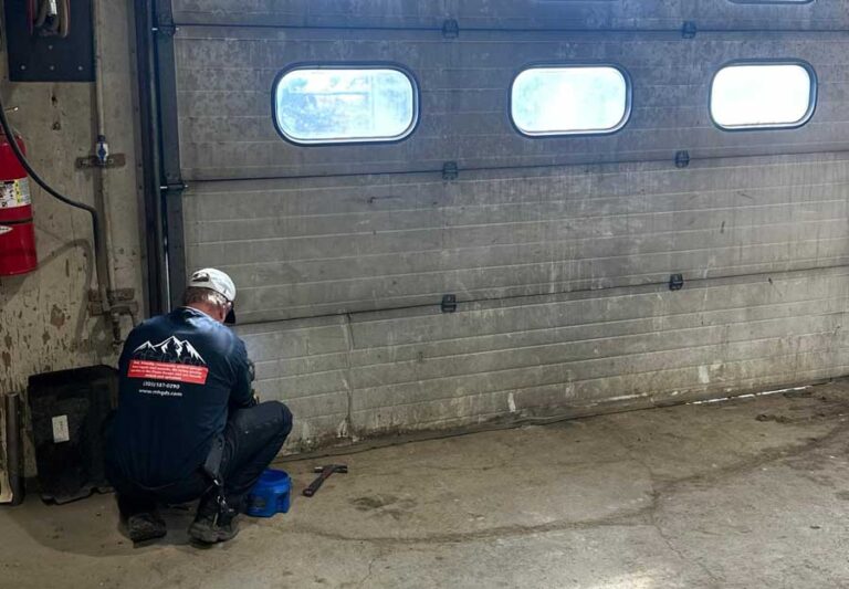 Technician repairing garage door in workshop.