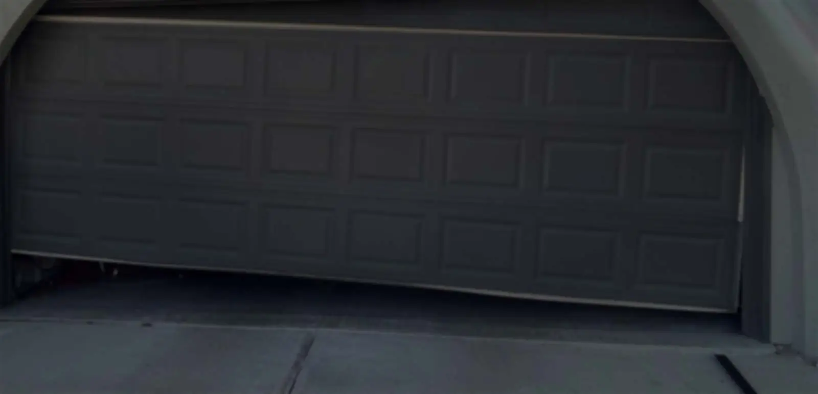 Partially open garage door with bent panel.