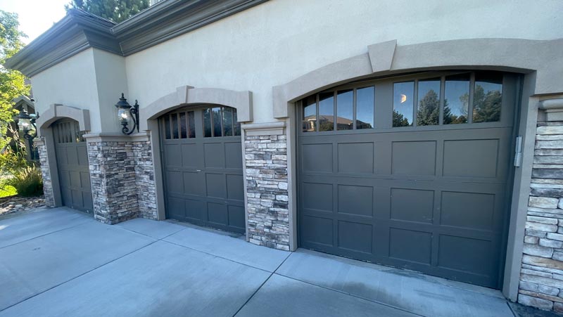Three elegant stone-trim garage doors with windows