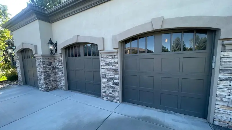 Three elegant stone-trim garage doors with windows
