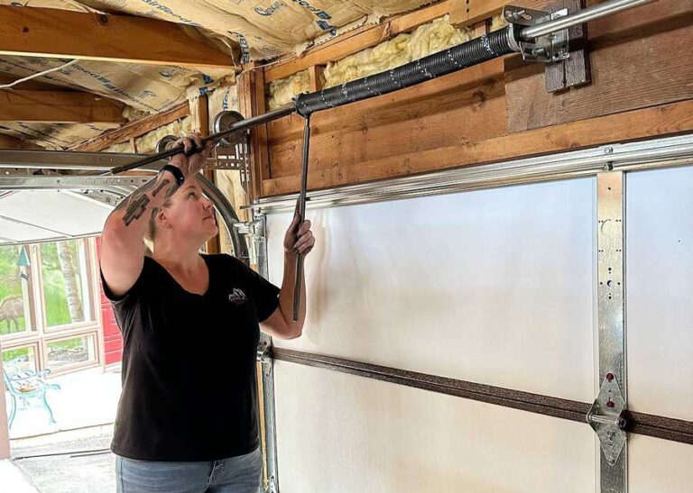 Woman adjusting garage door spring.
