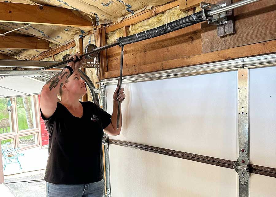 Woman adjusting garage door spring.