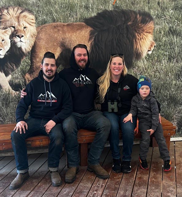 Group sitting on bench with lion backdrop.