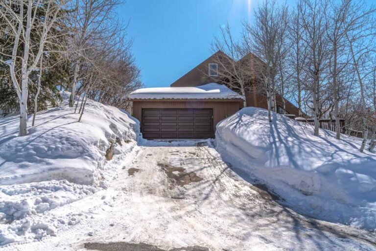 Snowy driveway leading to a garage