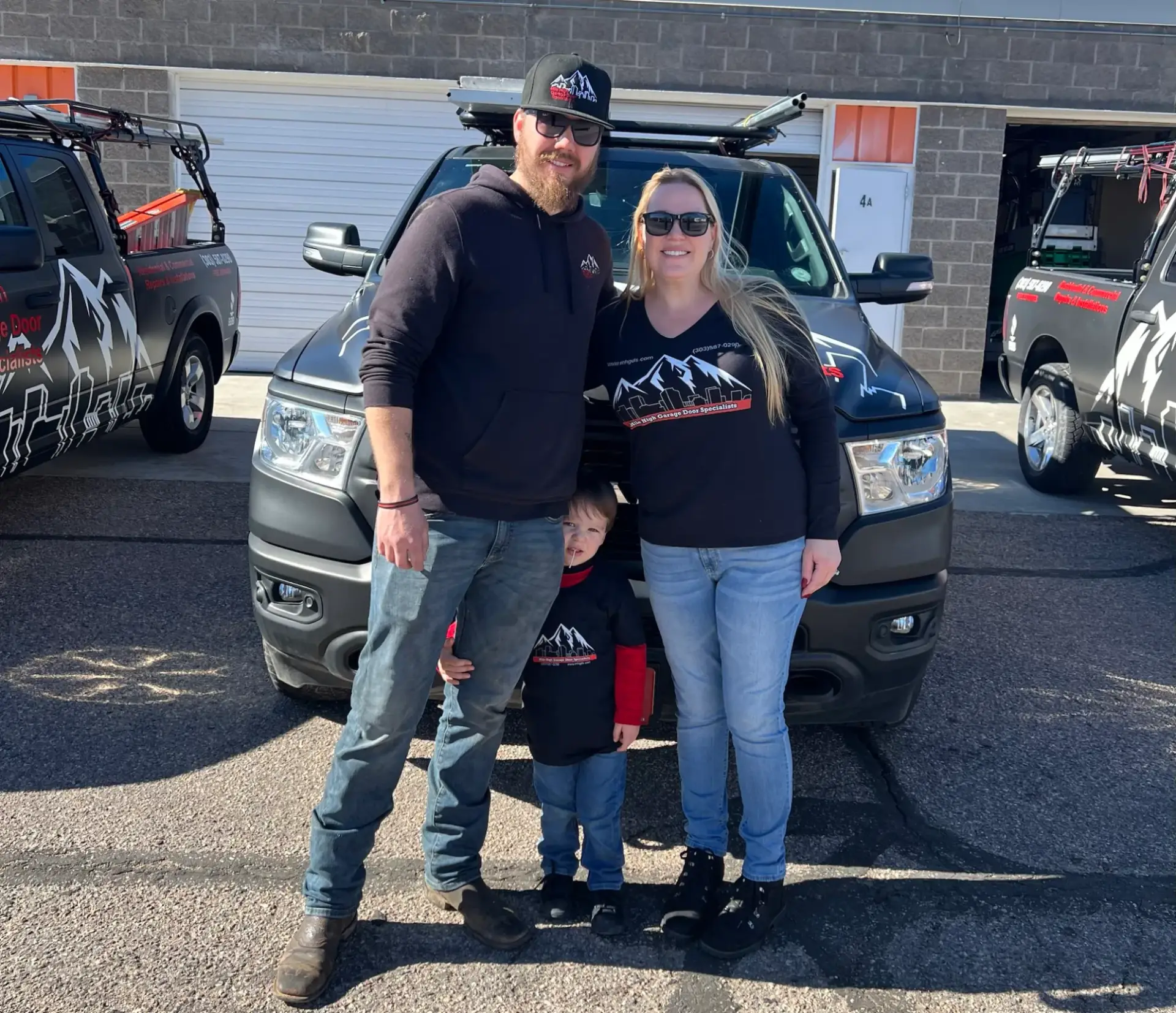 Family in front of branded trucks outdoors.
