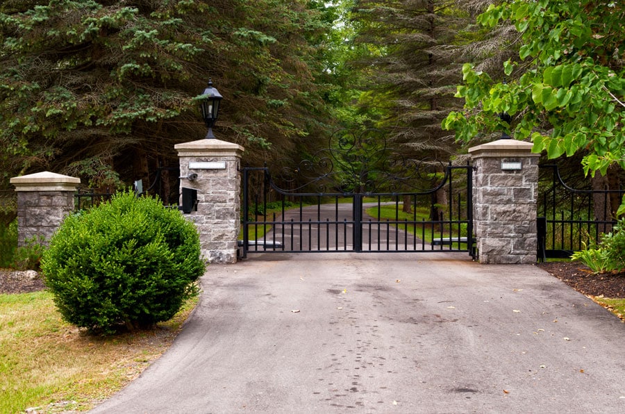 Gated driveway with stone pillars and trees.